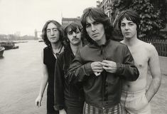 the rolling stones posing for a black and white photo in front of a river with boats