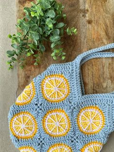 a crocheted purse sitting on top of a wooden table next to a plant