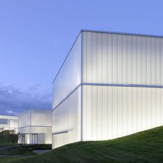 two large white buildings sitting on top of a lush green hillside next to each other