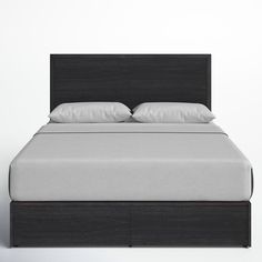 a bed with white pillows and black headboard