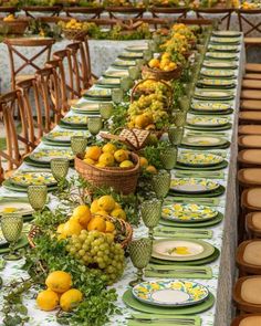 a long table with plates, bowls and baskets filled with fruit on top of it