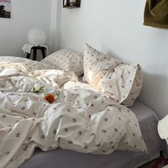 an unmade bed with white sheets and flowers on it