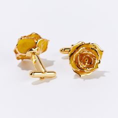 two gold cufflinks with yellow flowers on them, one in the shape of a rose