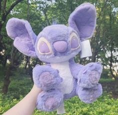 a purple stuffed animal is held in the air