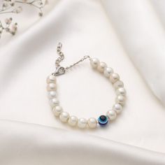 Crafted with meticulous attention to detail, the bracelet features lustrous white beads that delicately encircle the wrist, creating a timeless and versatile piece that complements any outfit. The centerpiece of this enchanting bracelet is the captivating Evil Eye charm, adorned with intricate beading and a mesmerizing white and blue eye. Adjustable Pearl White Bracelet As Gift, Adjustable Pearl White Bracelet For Gift, Adjustable Pearl White Pearl Bracelet As Gift, Adjustable Pearl White Pearl Bracelet For Gift, Adjustable Pearl Chain Bracelets Gift, Adjustable Pearl Chain Bracelets As Gift, Adjustable Pearl Chain Bracelet For Gift, White Round Jewelry For Friendship, Elegant Beaded Evil Eye Bracelet With Round Beads