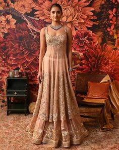 ‘Ethereal beauty’, is the word that comes instantly to mind while looking at this blush pink Anarkali. The Anarkali is a compilation of multi-generation vibes smoothly crafted in golden and silver embroidery work with floral motifs. Pair it up with some statement jewelry and watch everyone go gaga over your style. Sleeveless Anarkali kurta with dabka and nakshi embroidered yoke and hem SS zip closure in Anarkali and skirt Silver foil printed skirt with embroidery at the hem Floral embroidered pa Anarkali With Skirt, Lehanga Blouses, Floral Anarkali Dresses, Silver Embroidery Work, Suits For Women Stylish, Foil Print Dress, Sleeveless Anarkali, Organza Anarkali, Indian Dresses Anarkali