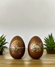 two brown eggs sitting on top of a wooden table next to succulents