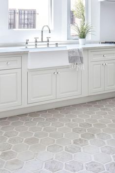 a kitchen with white cabinets and tile flooring in the center, along with a large window