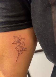 a woman's thigh with a small flower tattoo on her left side ribcage