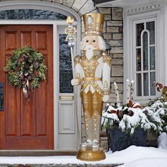 a gold and white nutcracker statue in front of a house with christmas wreaths