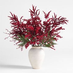 a white vase filled with red flowers on top of a table