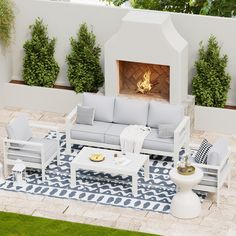 an outdoor living room with white furniture and a fire place in the fireplace behind it