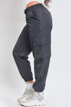 Somedays, getting dressed should just be easy. With a straightforward design, our Women’s High Rise Nylon Cargo Jogger is a true no-fuss pant. These high waisted pants feature an elasticized waistband with an adjustable bungee cord for customizable comfort and fit. They have subtle slant front pockets, side flap cargo pockets, and adjustable bungee hems for a cinched look at the ankle. Pair with a ribbed tank and sneakers for an everyday sporty look, or heels and a bodysuit for something more pl Stringless Jogger Pants Pocket Side, Sporty Stretch Cargo Pants With Functional Drawstring, Sporty Stretch Cargo Pants With Drawstring, Stretch Pants With Functional Drawstring For Outdoor Activities, Stretch Pants With Functional Drawstring For Outdoor, High Waist Nylon Sports Pants, Stretch Nylon Joggers With Cargo Pockets, High Waist Nylon Cargo Pants With Pockets, Athleisure Nylon Bottoms With Cargo Pockets