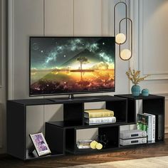 a flat screen tv sitting on top of a black entertainment center next to a book shelf