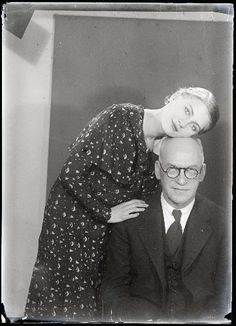 an old black and white photo of a man leaning on a woman's head