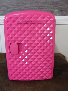 a pink plastic case sitting on top of a wooden table next to a white wall