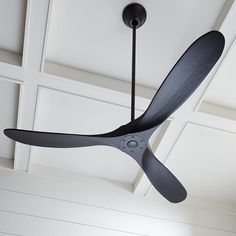 a black ceiling fan hanging from the ceiling in a room with white walls and paneled ceilings