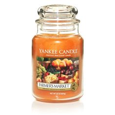 yankee candle jar filled with orange colored fruit and vegetables, on a white table top