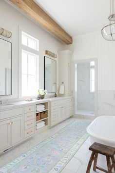 a large bathroom with white cabinets and marble counter tops, along with a blue rug on the floor