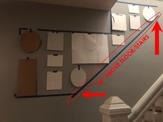 there are several pieces of paper on the wall next to the stair railing and above it is an arrow pointing up