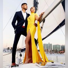 a man and woman standing on top of a sailboat in front of the ocean