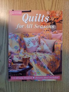 the cover of quilts for all seasons is displayed on a wooden table with a coffee table