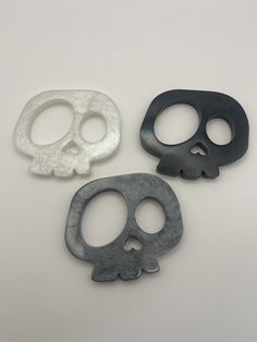 three different types of skull shaped objects on a white surface, one is black and the other is grey