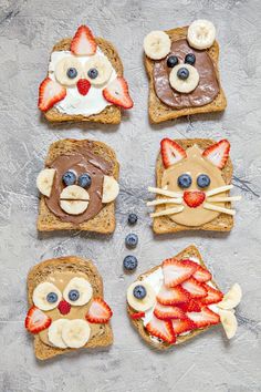 four slices of toast with fruit and chocolate on them, each decorated like a cat