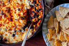 a plate of tortilla chips next to a casserole dish with black beans and corn