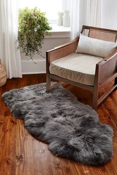 a white sheepskin rug is on the floor next to a chair and potted plant