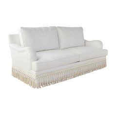 a white couch with fringe trim on the arms and back, sitting in front of a white background