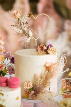 a white wedding cake with flowers on top and a heart shaped candle in the middle