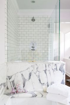 a marble bathtub in a bathroom with white tile walls and floors, along with towels on the floor