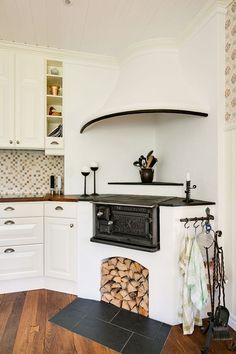 a stove top oven sitting inside of a kitchen next to a bunch of wood logs