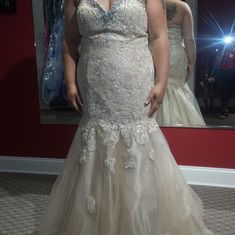 a woman is standing in front of a mirror wearing a wedding dress with flowers on it