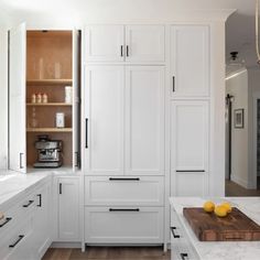 a kitchen with white cabinets and marble counter tops, along with wooden cutting board on the floor