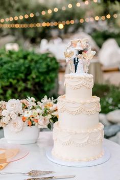 a wedding cake sitting on top of a table next to flowers and utensils