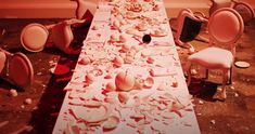 a long table is covered in confetti and pink chairs are scattered around it