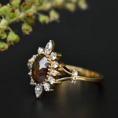 a close up of a ring on a black surface with flowers in the back ground