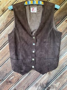 Very nice Swedish vintage soft dark brown genuine suede leather vest, fully lined. It has two pockets in the front Closure with metal push buttons. On the back side straps with metal buckle for better adjustment. Brand - PG Leather Fashion, Sweden Estimated time of creation, - 1990s Vest seems more for ladies, but could be easily incorporated also in men's wardrobe. No size tag available, but seems to fit S size. Kindly check measurments to ensure a proper fit  Material -  Genuine suede leather Cheap Vintage Brown Vest, Brown Leather Vest For Workwear, Classic Leather Vest With Button Closure, Leather Vest With Button Closure, Leather Sleeveless Vest With Button Closure, Sleeveless Leather Vest With Button Closure, 70s Inspired Outfits, Boho Country, Brown Vest