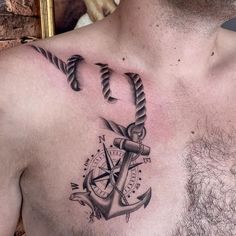 a man's chest with an anchor, compass and rope tattoo on his chest