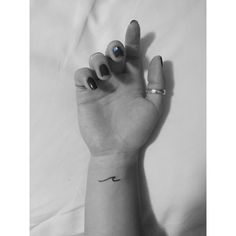 a woman's hand with a small wave tattoo on her left wrist and two fingers