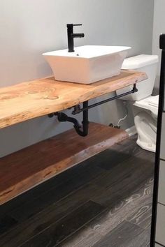 a white sink sitting on top of a wooden counter next to a toilet in a bathroom