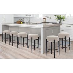 a kitchen island with four stools in front of it and a sink behind it