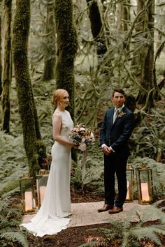 a bride and groom standing in the woods with lanterns lit up for their wedding ceremony