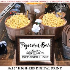 popcorn bar sign sitting on top of a table next to buckets filled with popcorn