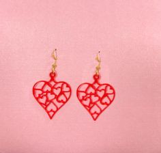 two red heart shaped earrings on a pink background with the word love written in it