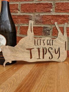 a wooden sign that says let's get tipsy next to a bottle of wine