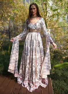 This elegant White Printed Satin Silk Anarkali Gown, crafted from luxurious satin silk, exudes graceful charm with its flowing design and intricate details. The white anarkali showcases mesmerizing printed motifs inspired by traditional patterns, accentuated by delicate waist embroidery for a touch of regal opulence. Featuring a flattering V-neckline and full-length sleeves, the Anarkali flows effortlessly, creating captivating movement with every step. Paired with a comfortable matching churida Off White Anarkali Gown With Dupatta, Bollywood Style White Maxi Dress For Festivals, Traditional White Maxi Dress For Navratri, Off White Anarkali Floor-length Gown, White Traditional Drape Maxi Dress For Navratri, White Maxi Dress For Navratri With Traditional Drape, Off White Floor-length Anarkali Gown, White Maxi Dress With Traditional Drape For Navratri, White Long Sleeve Maxi Dress For Navratri