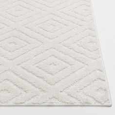 a white rug with diamond shapes on the top and bottom, against a white background